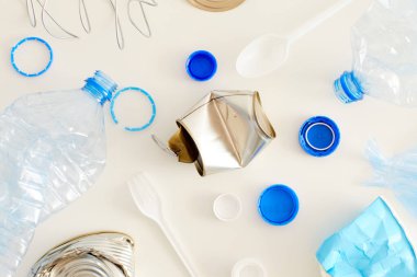 Beyaz arkaplan, atık sıralama ve geri dönüşüm kavramı üzerine minimum kompozisyonda yerleştirilen çeşitli çöp ögelerinin üst görünümü, kopyalama alanı