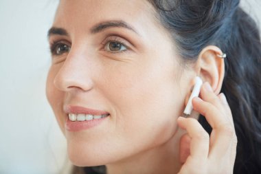 Kablosuz kulaklıklarıyla müzik dinleyen genç beyaz kadının yatay yakın plan portresi.