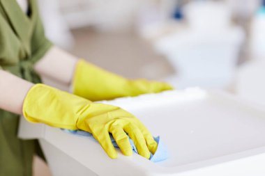 Evdeki plastik konteynırları temizlerken sarı lastik eldiven takan tanınmamış bir kadının fotoğrafını çek.