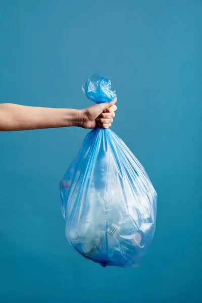 Pionowy Obraz Kobiecej Ręki Trzymającej Worek Śmieci Plastikiem Niebieskim Tle — Zdjęcie stockowe