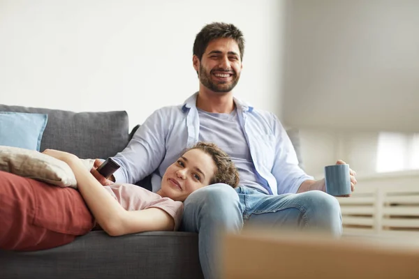 居心地の良いアパートで自宅でソファに座っている間に一緒にテレビを見て幸せなカップルの肖像画怠惰な時間を楽しんで スペースをコピー — ストック写真