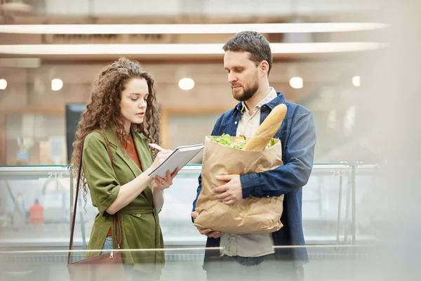 スーパーマーケットで食料品を購入しながら 現代のカップル読書ショッピングリストのウエストアップ肖像画 コピースペース — ストック写真