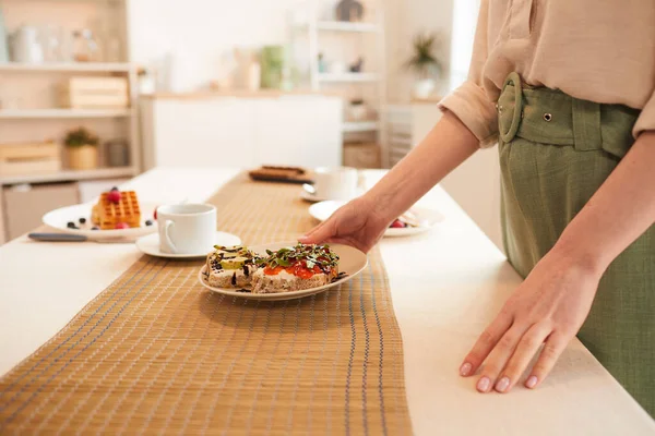 Sidovy Närbild Oigenkännlig Kvinna Sätta Frukosttallrik Matbord Minimal Kök Interiör — Stockfoto