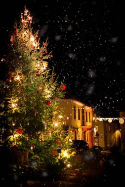 Kar yağışı sırasında romantik, ışıklı Noel ağacı