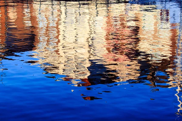 Reflexões de casas na água de um porto — Fotografia de Stock