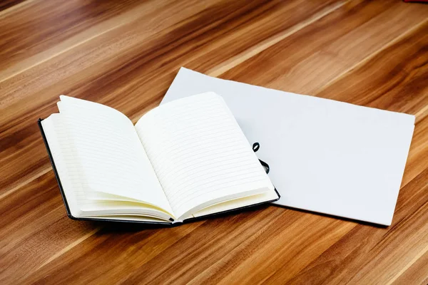 Blank newspaper and open notebook on a brown wooden table