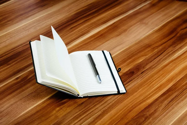 Apra il notebook e una penna su un tavolo di legno — Foto Stock