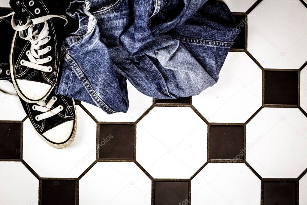 Jeans and sports shoes lying on the floor