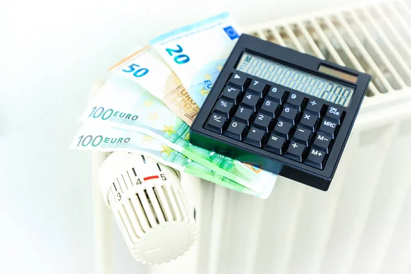 Деньги и калькулятор на радиаторе символизируют дорогое тепло — стоковое фото