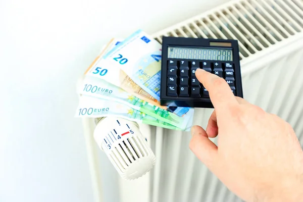 Dinero y calculadora en un radiador simboliza el calor caro —  Fotos de Stock