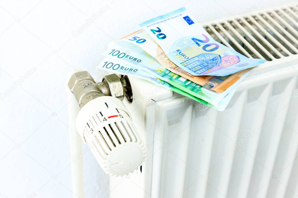 Money on a radiator symbolizes the expensive heating costs