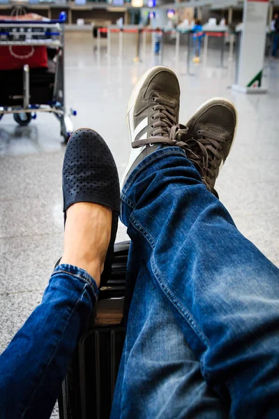 Kilka czeka na lotnisku z nogami na suitca — Zdjęcie stockowe