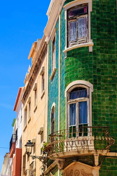Mediterranean house facade with green tiles and white windows