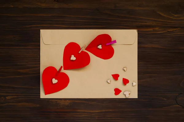 envelope with red hearts on a wooden background, the concept of Valentine\'s Day, top view