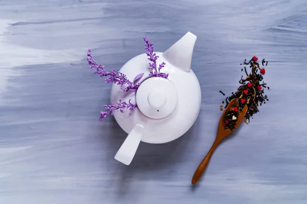 Tea gyógynövények ultraibolya színek a fehér kerámia teáskanna a világos fából készült háttér, fogalmának a tea szertartás, felülnézet — Stock Fotó