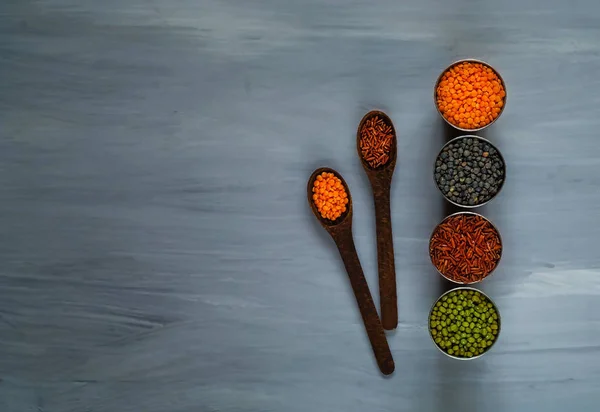 Cuchara de madera y varios cereales en copas de metal, el concepto de una alimentación saludable.Vista superior. Fondo blanco rústico con espacio libre de texto — Foto de Stock