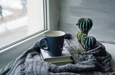 İskandinav tarzı, bir pencere bir yığın kitap arka planda örme bir doku üzerinde bir fincan