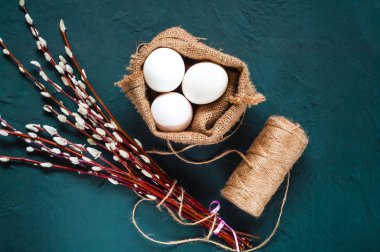 Paskalya bayram, bir söğüt dalı ve çuval bezi beton mavi arka plan, üstten görünüm üzerinde dekoratif renkli yumurta dekor