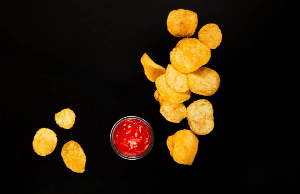 Chips mit Ketchup auf schwarzem Hintergrund, Platz für Text. Bequeme Zwischenmahlzeit — Stockfoto