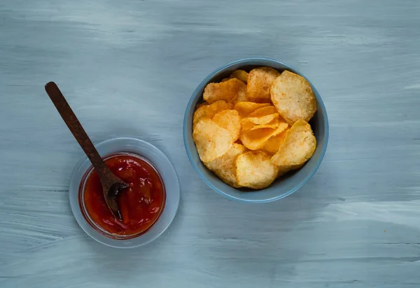 Patatas fritas en un tazón azul con salsa de tomate sobre un fondo azul claro, espacio para el texto. — Foto de Stock