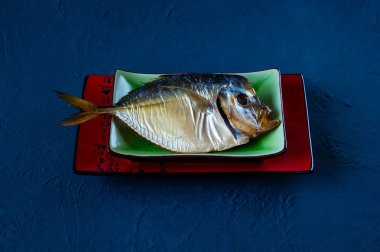 Mavi beton renkli arka plan üzerinde bir seramik tabak balık füme