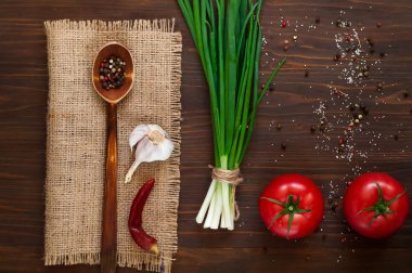  tahta kaşıkla baharat çuval bezi üzerinde ve ahşap arka plan kopya alanı üzerinde büyük kırmızı domates,