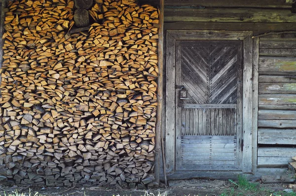 Authentic   wooden door on the background of firewood, concept of authentic objects in the wild, copy space — Stock Photo, Image