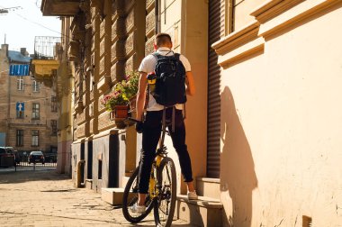 genç adam bir sabah şehrin, sağlıklı bir yaşam tarzı kavramı bir arka plan siyah bir sırt çantası ile sarı bir spor Bisiklet,
