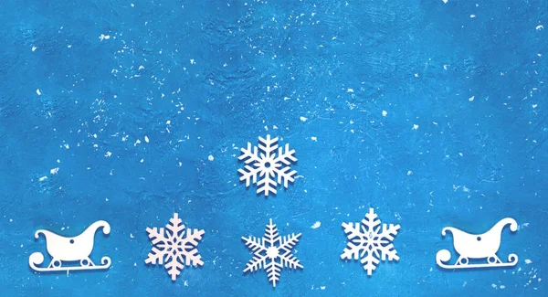 Copos de nieve decorativos de Navidad de madera y trineos sobre fondo azul. Tarjeta de Año Nuevo festiva en color de moda —  Fotos de Stock