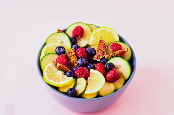 Fruktsallad av vilda bär och exotiska frukter på rosa bakgrund. Begreppet hälsosam kost, noll avfall. Närbild — Stockfoto
