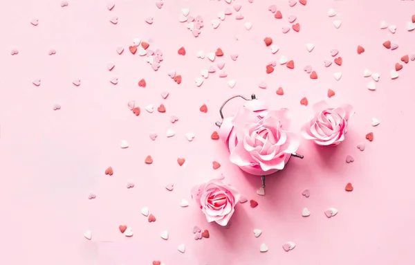 Εορταστική ιδέα με ξυπνητήρι και τριαντάφυλλα λουλούδι σε ροζ φόντο.Ημέρα του Αγίου Βαλεντίνου. Κοντινό πλάνο — Φωτογραφία Αρχείου