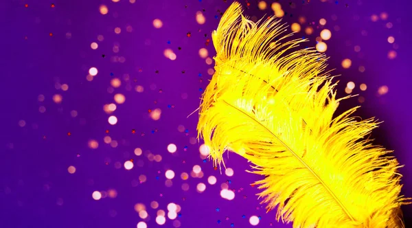 Žluté pštrosí peří na purpurovém pozadí s třpytkami. Čínská novoroční koncepce. Rekreační zázemí pro balení a projekty. Detailní záběr — Stock fotografie