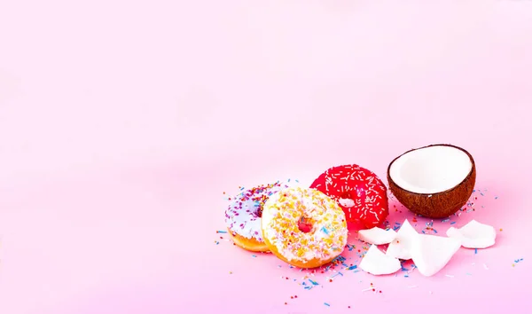 Μισή καρύδα και χρωματιστά ντόνατς με πολύχρωμα τρούφα σε ροζ φόντο. Αντιγραφή χώρου — Φωτογραφία Αρχείου