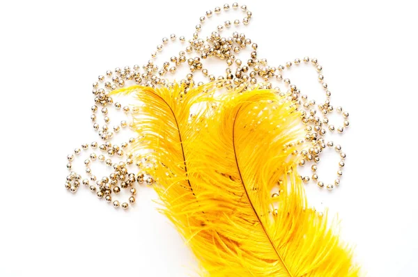 Plumas de avestruz amarillo sobre fondo blanco con cuentas de plata. Concepto de Mardi Gras. Antecedentes festivos para proyectos. Primer plano — Foto de Stock