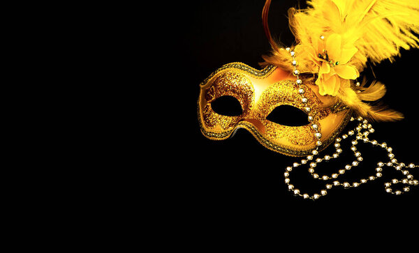 Golden Carnival mask on black background with silver beads. Mardi Gras concept. Copy space