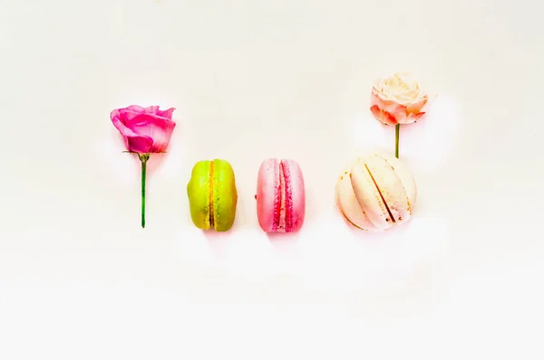 Composição festiva. Macaroons multicoloridos e flores de rosa em fundo branco isolado. Close-up — Fotografia de Stock