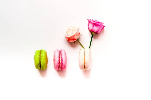 Composição festiva. Macaroons multicoloridos e flores de rosa em fundo branco isolado. Close-up — Fotografia de Stock