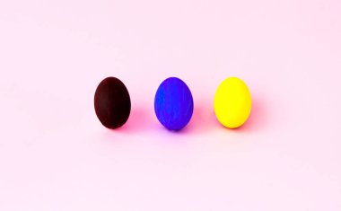 Pembe arka planda renkli paskalya yumurtaları. Kutlama konsepti, minimalizm. Yakın plan.