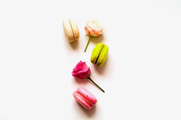 Kutlama kompozisyonu. İzole edilmiş beyaz arka planda çok renkli badem kurabiyeleri ve gül çiçekleri. Yakın plan. — Stok fotoğraf