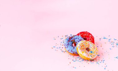 Çörek günü. Pembe arka planda renkli serpiştirilmiş ısırık renkli çörekler. Boşluğu kopyala, yakın plan