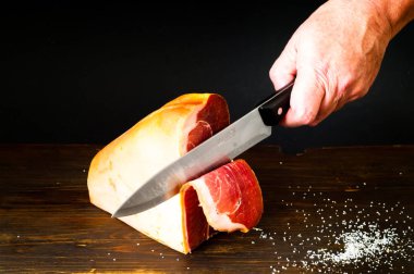 Tahta arka planda kurutulmuş İtalyan Prosciutto 'sunun dilimlenmesi. Yakın plan, kopyalama alanı