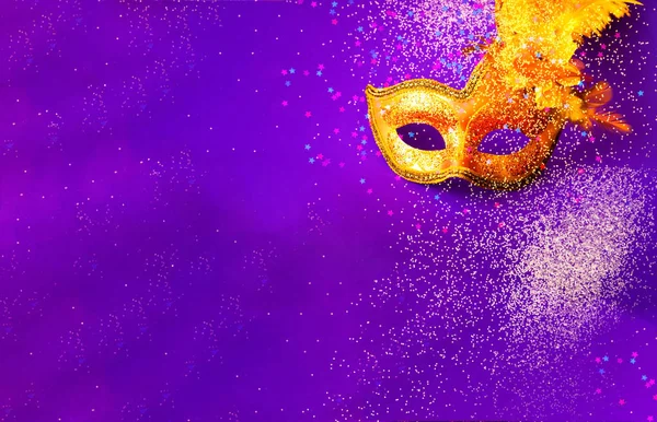 Golden Carnival mask on purple background with sparkles. Blurred effect. Mardi Gras concept. Copy space, close-up