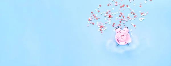 Pembe alarm saati ve konfetiyle yaratıcı mavi arka plan. Kutlama konsepti mi yoksa 