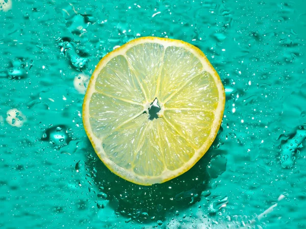 Cross-section of the juicy lemon on blue background with water drops