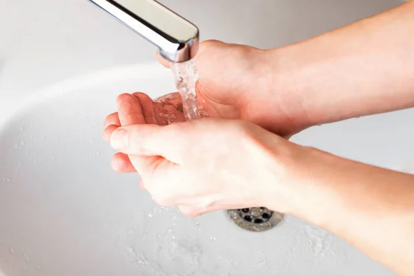 Washing hands under a stream of water  in the bathroom over the sink. Close-up of men\'s hands. Hygiene concept. Coronavirus, Covid-19