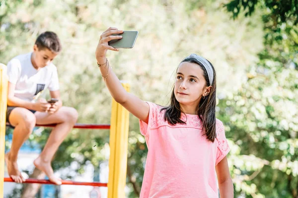 Kız parkta cep telefonuyla selfie çekiyor.