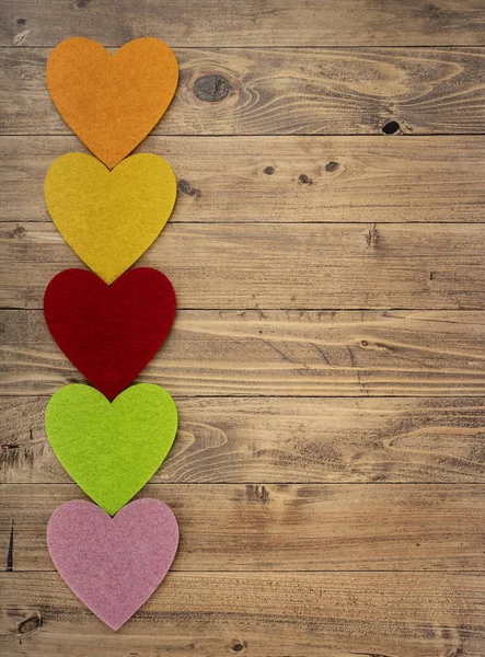 Colored hearts in a row down on a walnut wood background. Concept of St. Valentine's Day — Stock Photo, Image