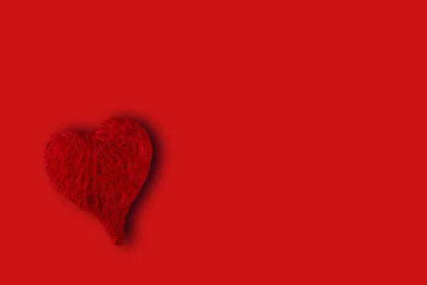 Red heart in the lower left corner on a red background. Concept of St. Valentine's Day — Stock Photo, Image