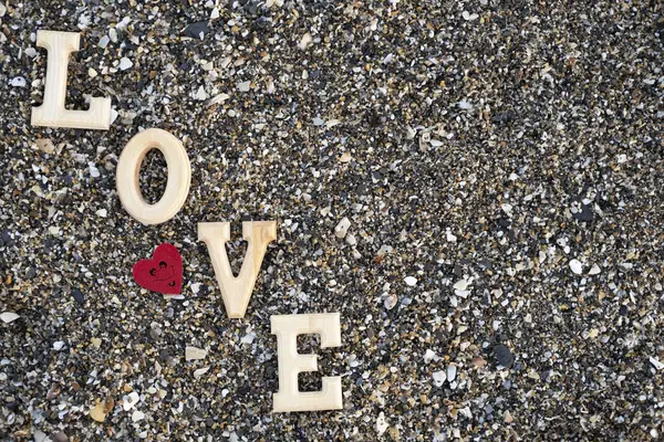 Wooden letters forming the word love with a red heart on a background of beach sand.concept valentine's day — Stock Photo, Image