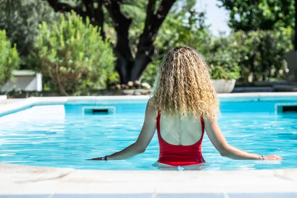 Mujer rubia con traje de baño rojo en la espalda en una piscina. concepto de verano — Foto de Stock